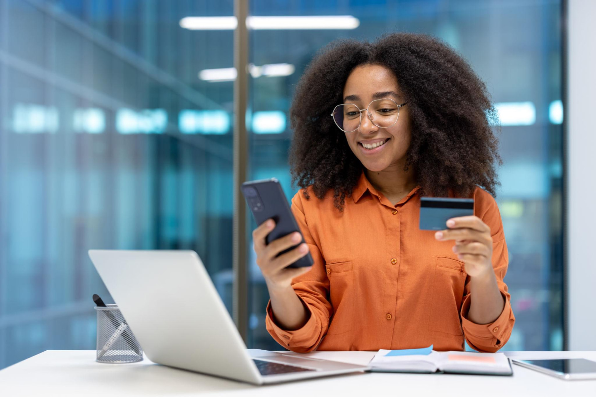 A young Black professional using her phone and payment card